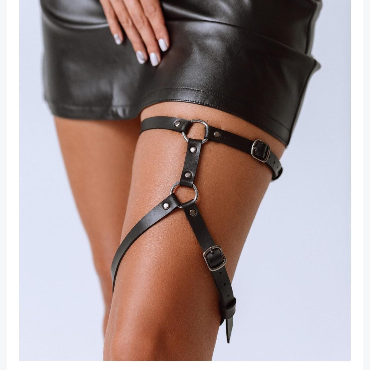 lack leather garter belt worn by a person on a light gray background